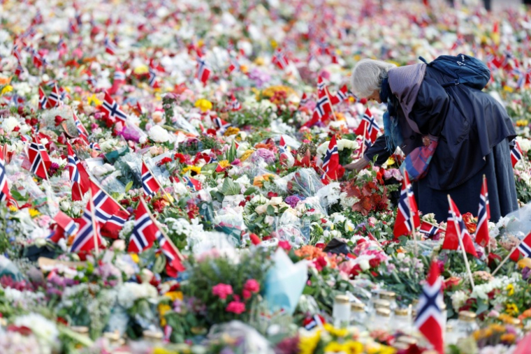 Une femme se tient au milieu d’un mémorial improvisé en hommage au roi Harald V de Norvège, décédé, sur la place du Palais royal à Oslo, le 31 août 2026 ( AFP / Odd ANDERSEN )
