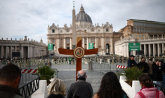 Des pèlerins portent une croix alors que le pape François est admis pour poursuivre son traitement
