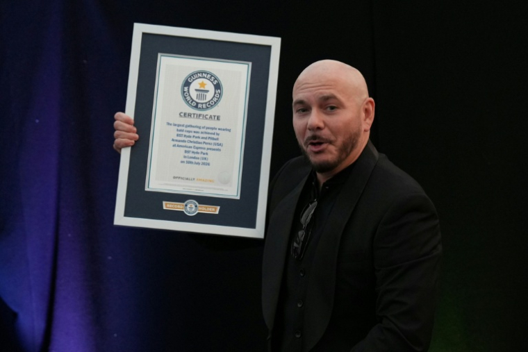 Le rappeur américain Pitbull pose avec son diplôme du Guinness des records grâce à un rassemblement de 22.141 fans portant de faux crânes chauves, le 10 juillet 2026 à Londres ( AFP / CARLOS JASSO )