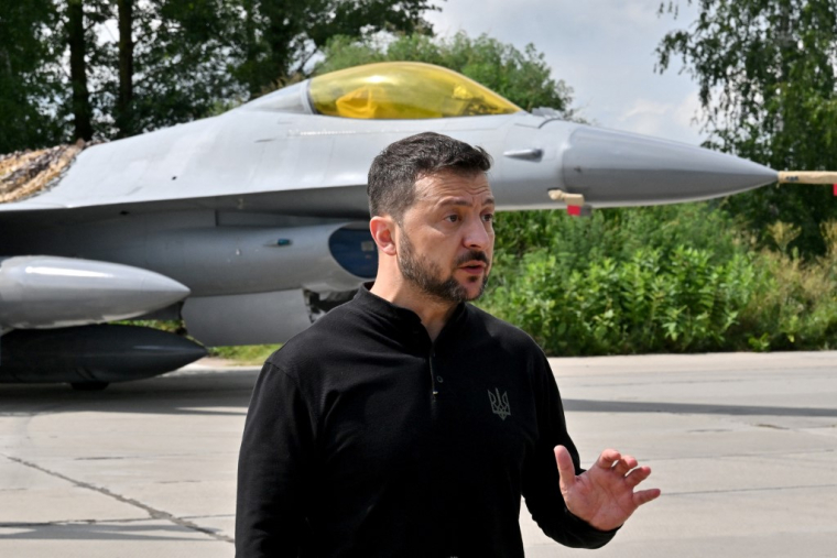 Volodymyr Zelensky, devant un F-16 de l'armée ukrainienne, le 4 août 2024 ( AFP / SERGEI SUPINSKY )