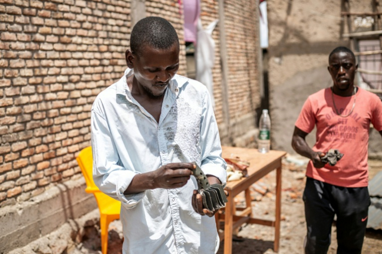 Un habitant de Bujumbura, au Burundi, observe le 1er avril 2026 un éclat d'obus tombé dans la nuit sur une école, après un incendie dans un arsenal militaire ayant déclenché des explosions de munitions ( AFP / Fabrice Mbonankira )