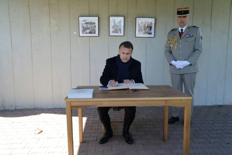 Le président français Emmanuel Macron (g) signe le livre d'or au cimetière militaire français, tandis qu'en arrière-plan apparaissent des photos de la visite officielle du président français Charles de Gaulle en 1967, le 20 avril 2026 à Gdansk, en Pologne ( AFP / Ludovic MARIN )