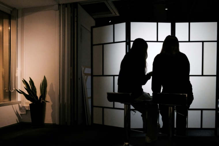 Des étudiantes de l'université de Hong Kong victimes de deepfakes pornographiques - B. et C. - regardent leur téléphone, le 29 juillet 2025 à Hong Kong ( AFP / Tommy WANG )
