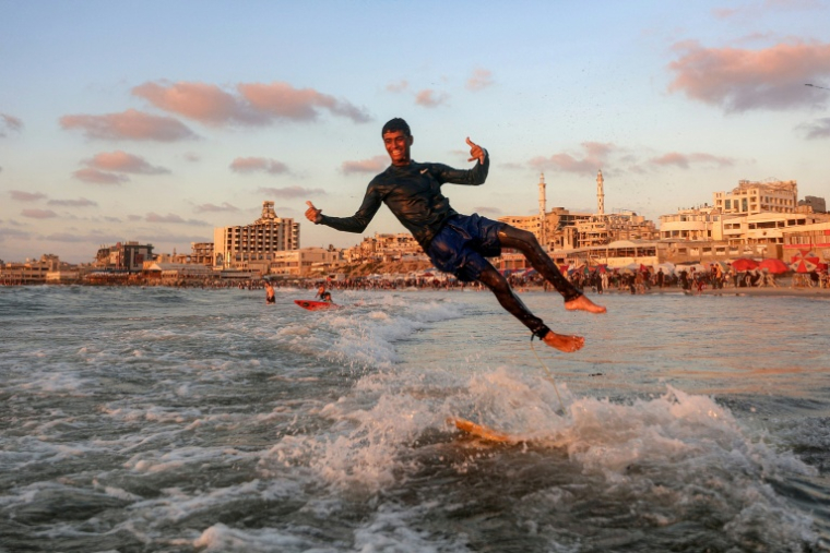 Un jeune Palestinien surfe au large d'une une plage de la ville de Gaza, le 21 juin 2026  ( AFP / Omar AL-QATTAA )