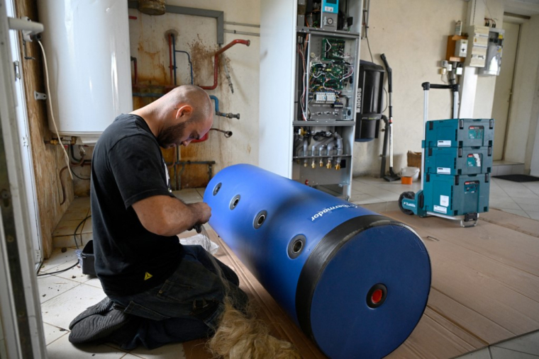 Un artisan installant une pome à chaleur. (illustration) ( AFP / DAMIEN MEYER )