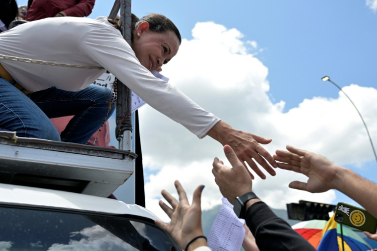 La cheffe de l'opposition au Venezuela, Maria Corina Machado (g), tend la main pour saluer ses partisans lors d'une manifestation à Caracas, le 17 août 2024 ( AFP / Juan BARRETO )