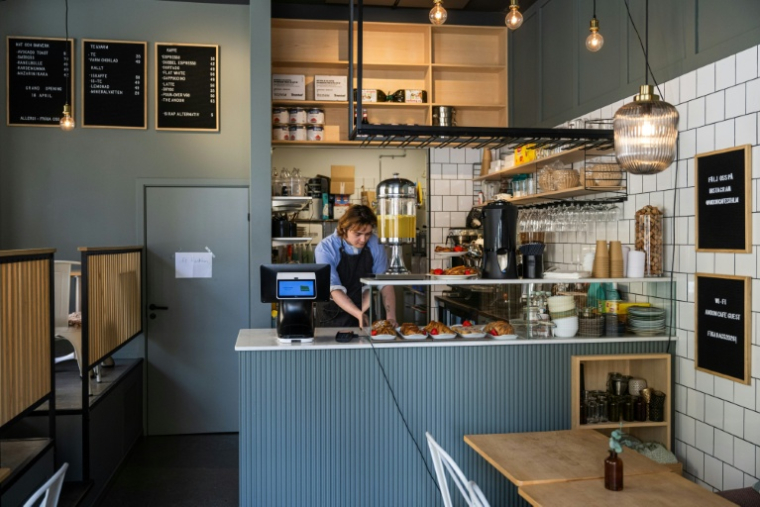 Kajetan Grzelczak derrière son comptoir  au café Andon à Stockholm, entièrement dirigé par l'IA, le 27 avril 2026 ( AFP / Jonathan NACKSTRAND )