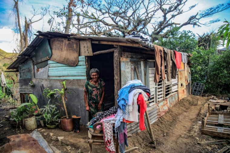 Une femme âgée devant la porte de sa maison, où sèche du linge au soleil, près de trois semaines après le passage de l'ouragan Melissa, à El Cobre, le 17 novembre 2025 à Cuba ( AFP / STRINGER )
