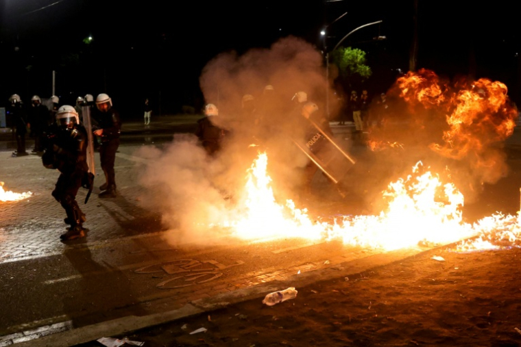Des membres des forces antiémeutes s’éloignent de cocktails Molotov en train de brûler, lors d’une manifestation antigouvernementale à Tirana, le 20 octobre 2026 en Albanie ( AFP / Adnan Beci )