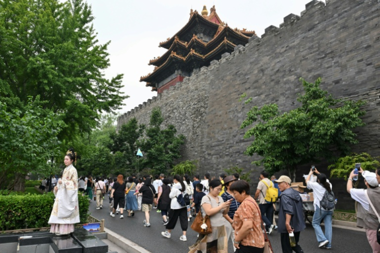 Une femme en robe traditionnelle (g) pose pour une photo alors que des touristes visitent la Cité Interdite à Pékin, le 11 juillet 2026 ( AFP / ADEK BERRY )