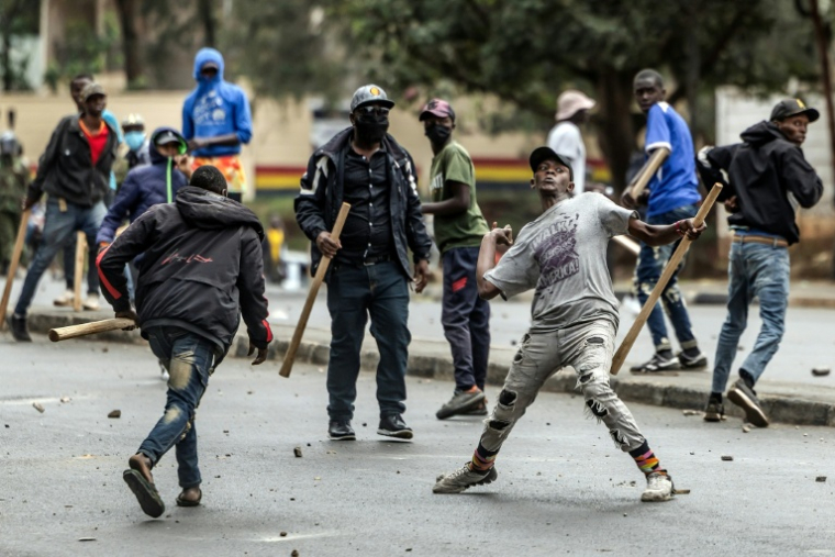 Des hommes armés de bâtons et de gourdins  lancent des pierres sur des manifestants, lors d'affrontements à Nairobi, le 17 juin 2025 au Kenya ( AFP / Luis TATO )