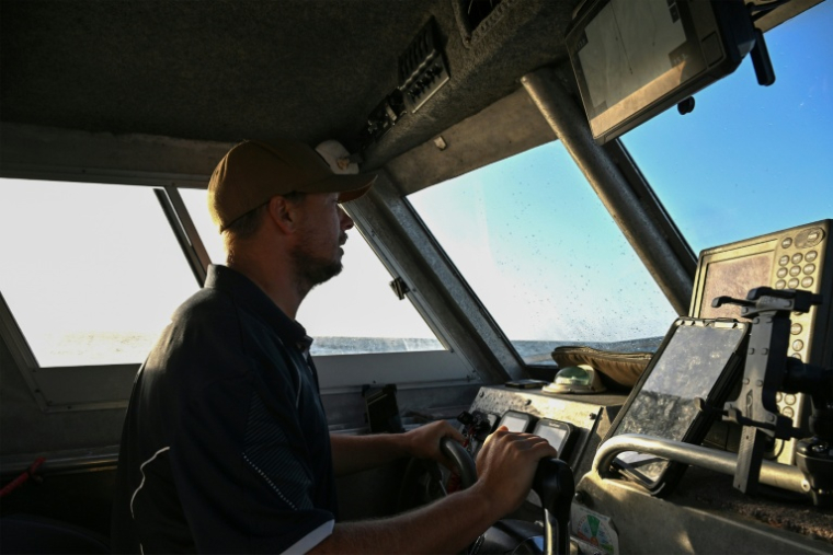 Un membre du programme de surveillance des requins s'approche d'un site pour récupérer des lignes de pêche intelligentes équipées d'hameçons appâtés, près de Coffs Harbour, en Nouvelle-Galles du Sud, le 10 novembre 2025 en Australie ( AFP / Saeed KHAN )