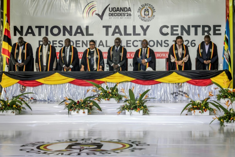 Des hauts responsables de la Commission électorale ougandaise se tiennent debout lors de l'annonce des résultats partiels de l'élection présidentielle ougandaise de 2026, alors que le dépouillement des votes se poursuit au Centre national de comptage à Kampala, le 16 janvier 2026. ( AFP / Luis TATO )