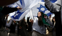 Des personnes dansent sous des drapeaux israéliens lors d'un événement commémoratif organisé par la communauté juive pour honorer les vies perdues lors de l'attaque du Hamas le 7 octobre 2023, à Londres, le 5 octobre 2025 ( AFP / HENRY NICHOLLS )