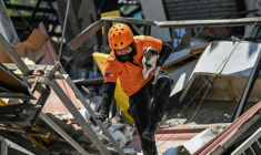 Un secouriste porte un chien de sauvetage lors d'opérations de recherche au niveau d'un bâtiment effondré, le 9 juin 2026 à General Santos aux Philippines ( AFP / Jam STA ROSA )