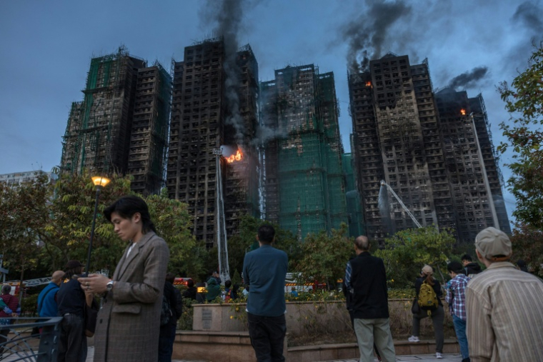 De la fumée s'échappe des immeubles après un incendie mortel dans le district Tai Po de Hong Kong le 27 novembre 2025 ( AFP / Dale DE LA REY )