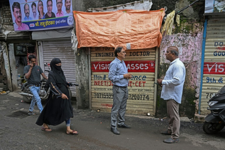 Ullesh Gajakosh (d), organisateur de la campagne "Sauvons Dharavi" dans une rue du bidonville de Bombay, le 8 juillet 2025 en Inde ( AFP / Indranil MUKHERJEE )