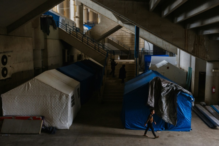 Un enfant passe devant des tentes installées dans le stade Camille Chamoun, transformé en centre d'accueil et d'hébergement pour personnes déplacées à Beyrouth, le 27 mars 2026 au Liban ( AFP / Dimitar DILKOFF )