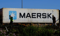 Des travailleurs parlent sur leur téléphones portables, alors qu'un conteneur Maersk est transporté par un train, près du port de Barcelone