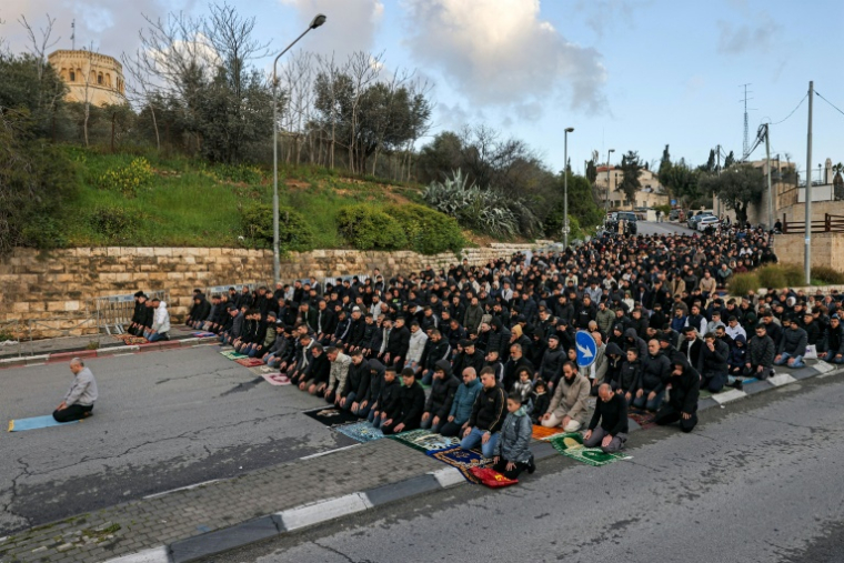 Des fidèles musulmans improvisent une prière devant les murailles de la Vieille ville de Jérusalem, le 20 mars 2026 ( AFP / AHMAD GHARABLI )