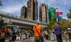 Des passants regardent les tours du coplexe complexe résidentiel Wang Fuk Court ravagées par un incendie, le 28 novembre 2025 à Hong Kong ( AFP / Dale DE LA REY )