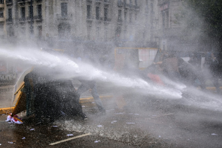 Des manifestants se protègent d'un canon à eau de la police, le 15 octobre 2026 à Buenos Aires, en Argentine ( AFP / Emiliano Lasalvia )