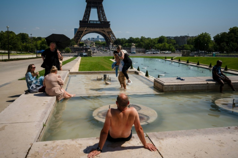 Des touristes se rafraîchissent au bassin de la place du Trocadéro à Paris le 1er juillet 2025 ( AFP / Dimitar DILKOFF )