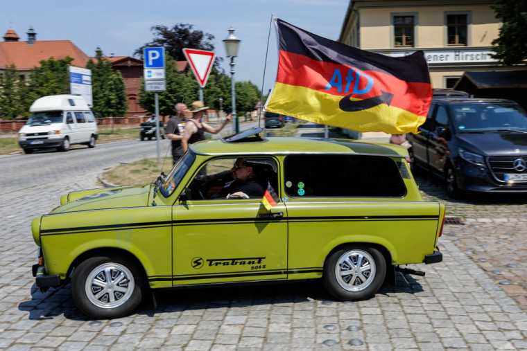 Un militant de l'AFD dans une voiture est-allemande de marque Trabant, à Oranienbaum, en Allemagne, le 28 juin 2026. ( AFP / JENS SCHLUTER )