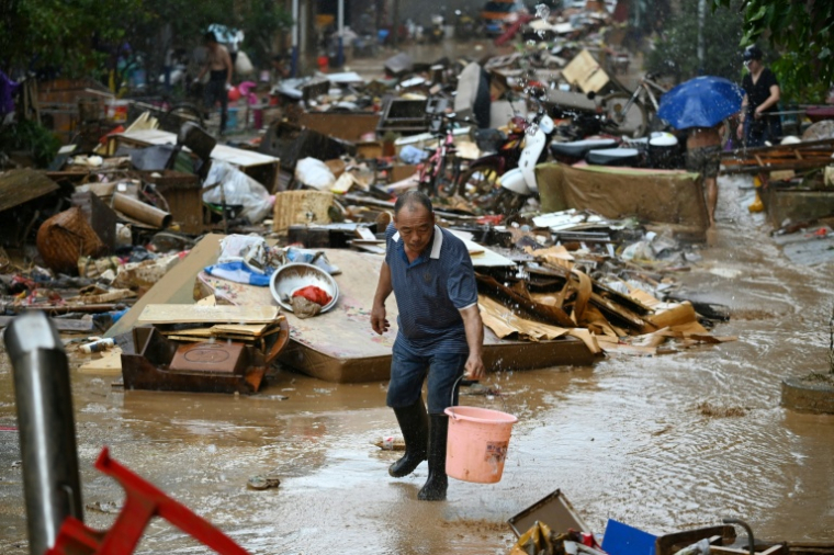 Un habitant récupère de l'eau de pluie dans une zone inondée après la rupture d'un réservoir près de Gantang, dans la région du Guangxi, le 9 juillet 2026 dans le sud-ouest de la Chine ( AFP / GREG BAKER )