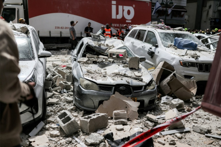 Des secouristes se tiennent derrière des véhicules endommagés par une attaque iranienne à Ramat Gan, dans le centre d’Israël, le 6 avril 2026 ( AFP / Ilia YEFIMOVICH )