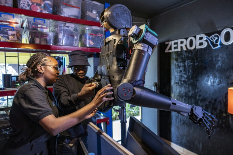 Norah Kimathi (G) confondatrice de la startup kényane ZeroBionic, et son directeur technique, l'ingénieur kényan Darell Adero programment le 19 août 2026 un robot humanoïde dans le laboratoire de l'entreprise à Nairobi ( AFP / SIMON MAINA )