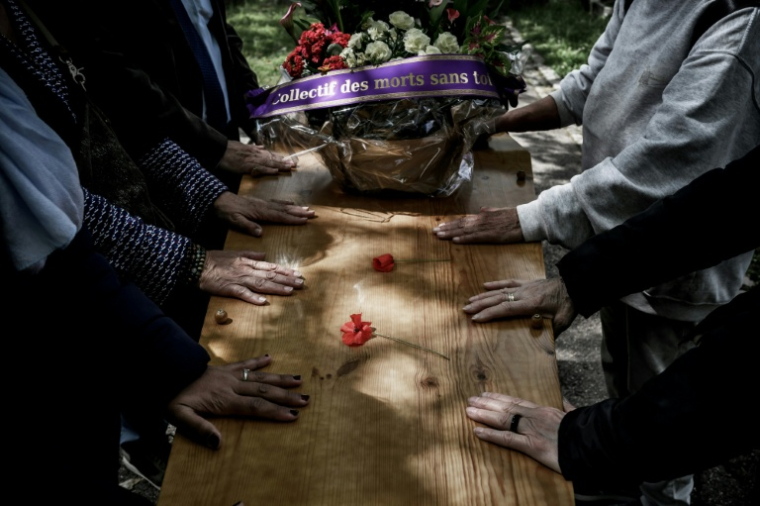 Des membres du collectif "Morts sans Toi(t)" se recueillent devant le cercueil d'une personne décédée seule au cimetière de La Guillotière, le 11 mai 2026 à Lyon,dans le Rhône  ( AFP / Jeff PACHOUD )