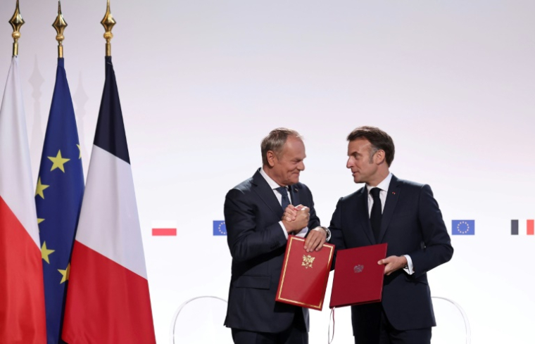 Le Premier ministre polonais Donald Tusk (g) et le président français Emmanuel Macron se serrent la main après avoir signé un traité à l'issue de leur rencontre à Nancy, le 9 mai 2025 ( POOL / Christophe PETIT TESSON )
