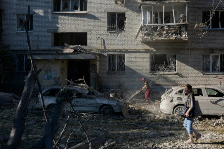 Une femme marche près d'un immeuble résidentiel endommagé à la suite d'une frappe à Kiev, le 20 août 2026 ( AFP / Tetiana DZHAFAROVA )