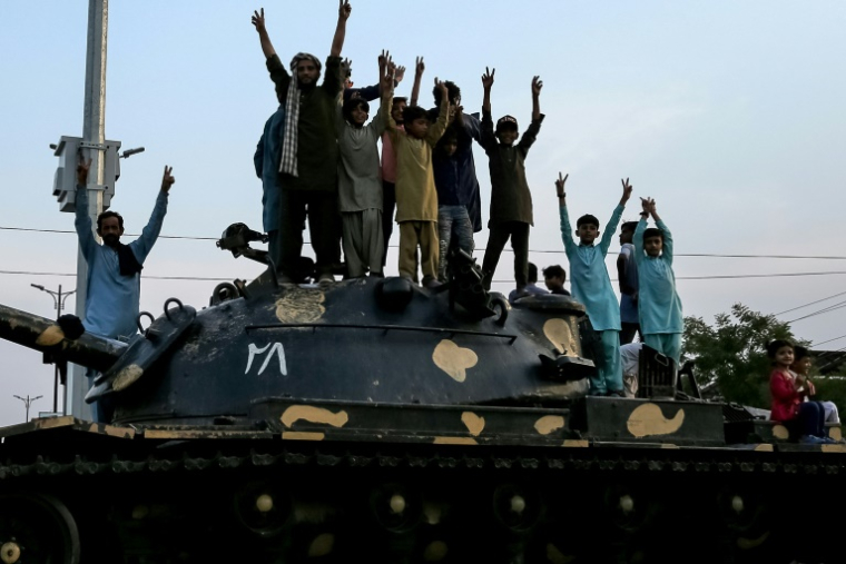Des Pakistanais grimpés sur un char célèbrent l'annonce du cessez-le-feu entre le Pakistan et l'Inde, à Multan, le 10 mai 2025 ( AFP / Shahid Saeed MIRZA )