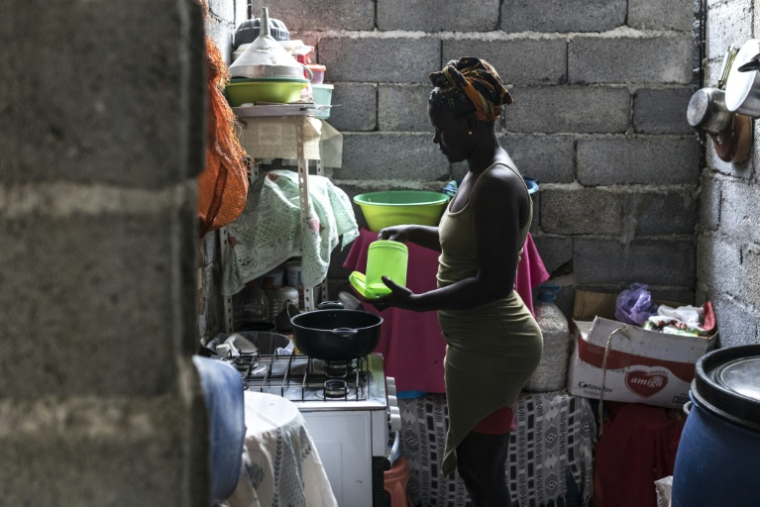 Vania Tavares cuisine chez elle avant de se rendre à la plage pour extraire du sable noir destiné à la vente, à Charco, le 20 mai 2026 au Cap-Vert ( AFP / PATRICK MEINHARDT )