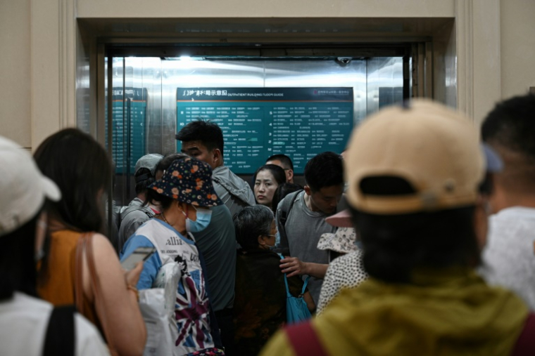 Des personnes attendant pour prendre un ascenseur bondé dans un hôpital à Pékin, le 23 juin 2025 en Chine ( AFP / Jade GAO )