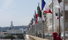 Une femme se tient près des drapeaux algérien et français avant l'arrivée du président français Emmanuel Macron à Alger