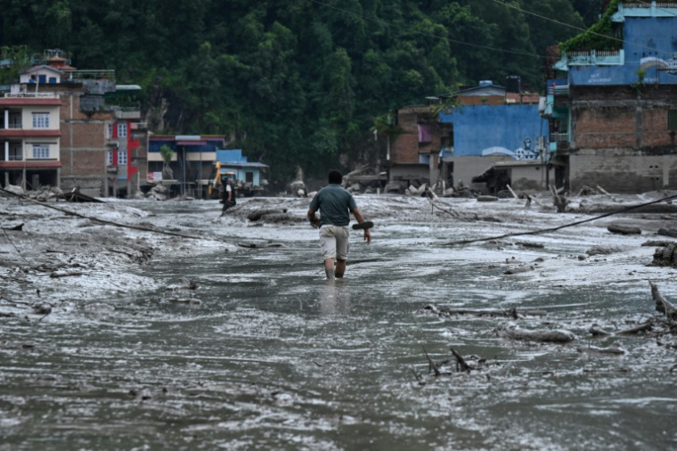 Un habitant marche dans une rue inondée de boue à Devighat, dans le district de Nuwakot au Népal, le 26 août 2026 ( AFP / PRAKASH MATHEMA )