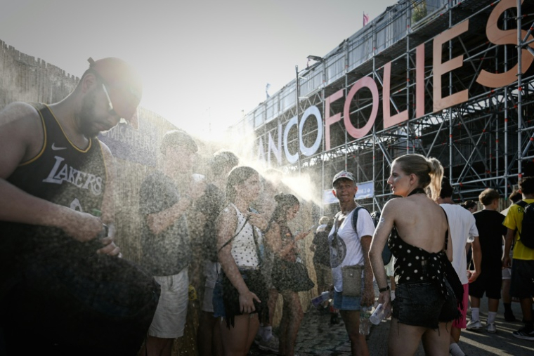 Des festivaliers se rafraîchissent à l'aide de brumisateurs aux Francofolies de La Rochelle, le 11 juillet 2026 ( AFP / Philippe LOPEZ )