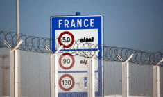 Un panneau frontalier est photographié derrière la clôture du port de Calais