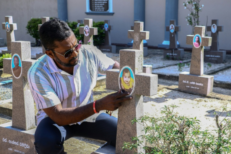 Dinal Fernando, un cadre commercial rescapé des attentats de Pâques en 2019, se recueille sur la tombe d'un bébé de huit mois tué lors des attaques, le 17 avril 2026 à l'église Saint-Sébastien du village de Katuwapitiya, au Sri Lanka ( AFP / - )