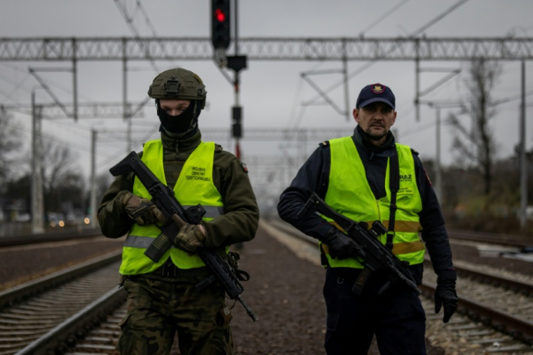 Un garde de la sécurité ferroviaire et un soldat des Forces de défense territoriale patrouillent le long des voies ferrées dans la banlieue de Varsovie, le 27 novembre 2025 en Pologne ( AFP / Wojtek RADWANSKI )