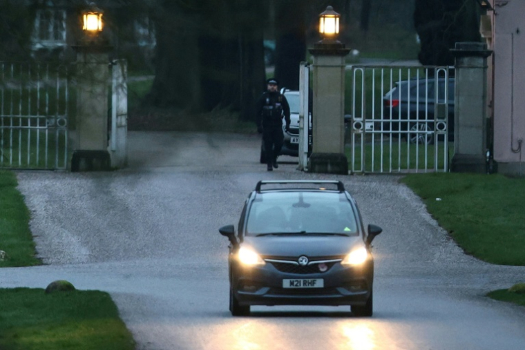 Un policier à l'entrée du Royal Lodge, ancienne résidence du prince Andrew, alors qu'une voiture s'éloigne dans le parc de Windsor, le 19 février 2026 à Windsor ( AFP / Toby Shepheard )