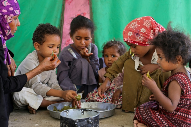 Saeedah Mohammed, une déplacée yéménite, nourrit ses petits-enfants avec des feuilles bouillies dans leur tente du camp d'Al-Manij, près de Taëz, dans le sud ouest du Yémen, le 21 mai 2026 ( AFP / Ahmed al-Basha )