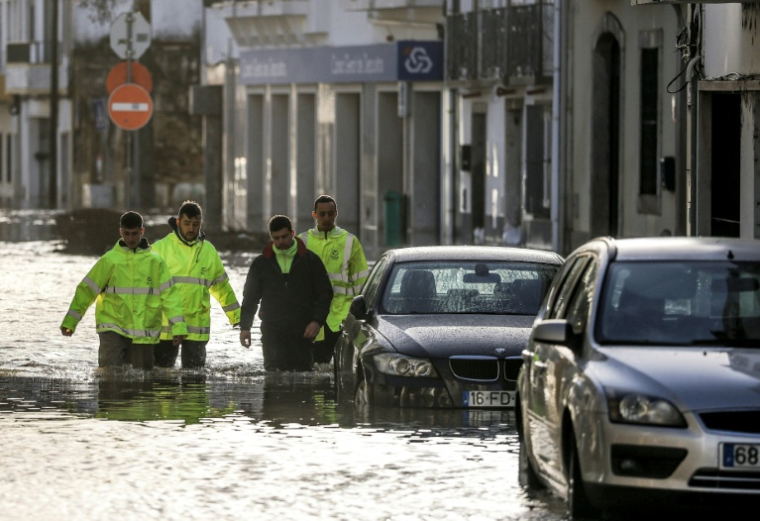 Des employés municipaux dans une rue inondée par les eaux de crue du fleuve Sado à Alcacer do Sal, pendant la dépression Leonardo, le 5 février 2026 dans le sud du Portugal ( AFP / PATRICIA DE MELO MOREIRA )