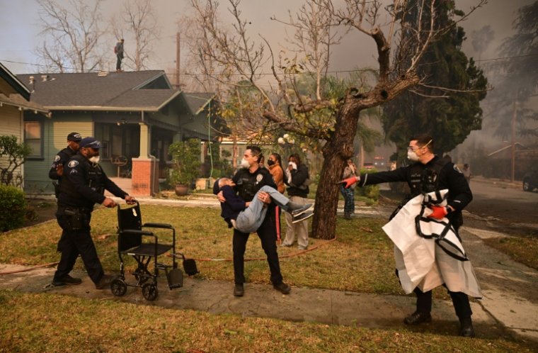 Des policiers évacuant une personne âgée de sa résidence lors de l'incendie ayant frappé Altadena, près de Los Angeles en Californie, le 8 janvier 2025 ( AFP / Robyn Beck )