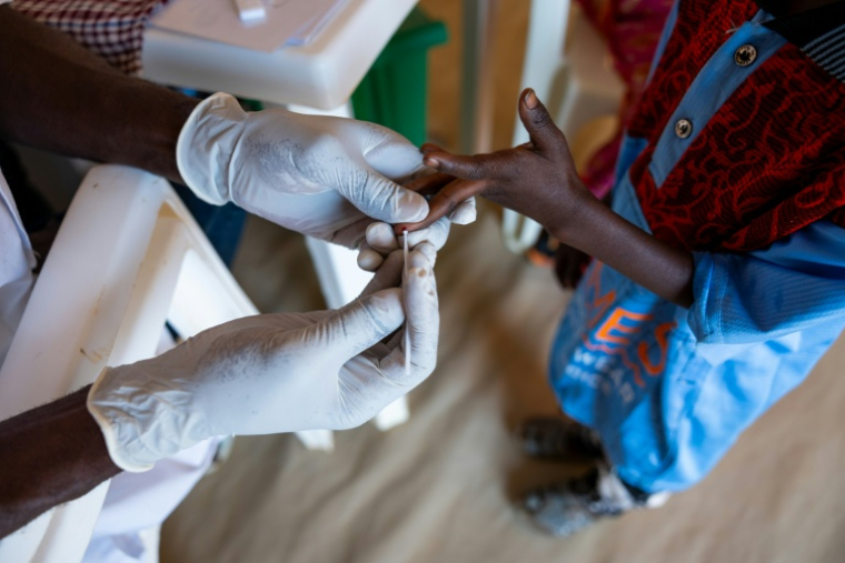 Une infirmière effectue un test de dépistage du paludisme sur un enfant soudanais souffrant de malnutrition, à l'hôpital MSF du camp de réfugiés de Touloum, dans la province de Wadi Fira, le 11 avril 2025 au Tchad  ( AFP / Joris Bolomey )