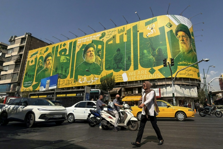 Des piétons et des automobilistes passent devant un panneau d'affichage géant représentant le chef assassiné du Hezbollah libanais, Hassan Nasrallah (G), et le guide suprême défunt iranien, l'ayatollah Ali Khamenei (D), le 27 septembre 2026 à Téhéran ( AFP / ATTA KENARE )