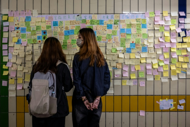 Des messages manuscrits laissés à l'intention des victimes collés sur le mur d'un tunnel piétonnier près des immeubles d'habitation de Wang Fuk Court, après l'incendie meurtrier du 26 novembre, le 1er décembre 2025 à Hong Kong ( AFP / Philip FONG )